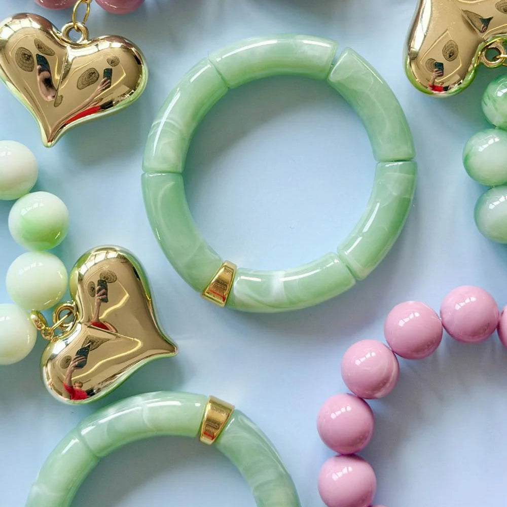 Colorful bracelets with heart charms on a light blue background