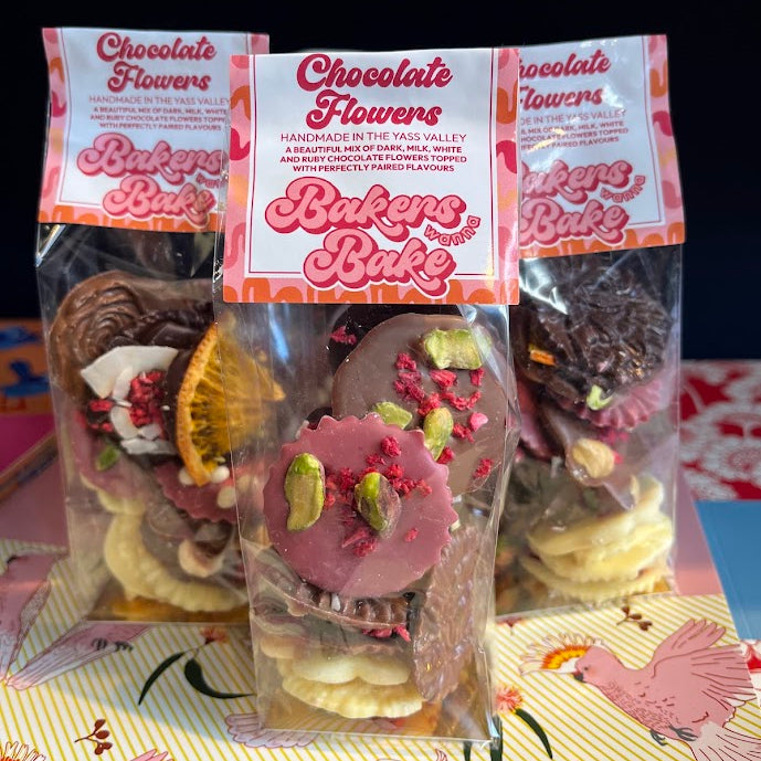 Three clear plastic bags of chocolate flower treats with pink and white labels reading 'Chocolate Flowers'
