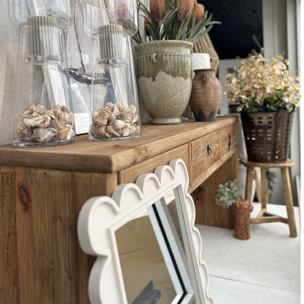 Wooden console table with decorative items including vases and a mirror.