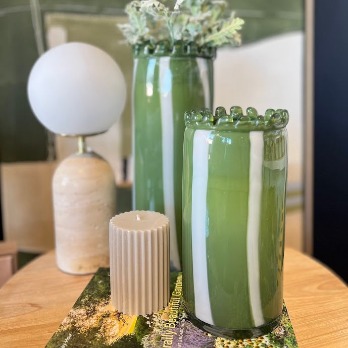 Green and white striped vase with decorative elements on a table