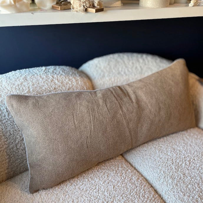 Long Lumbar Cushion on boucle lounge with decorative items in the background