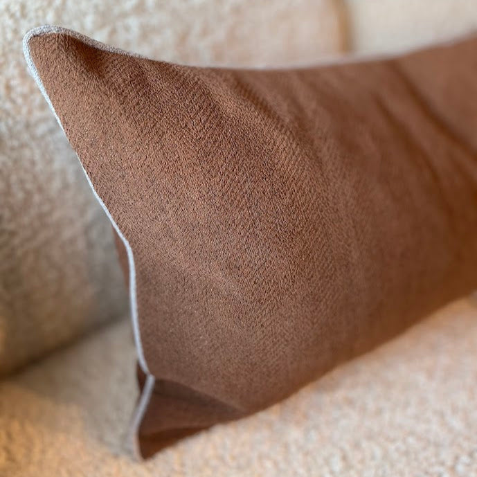 Close-up of a linen lumbar cushion in terracotta on boucle lounge
