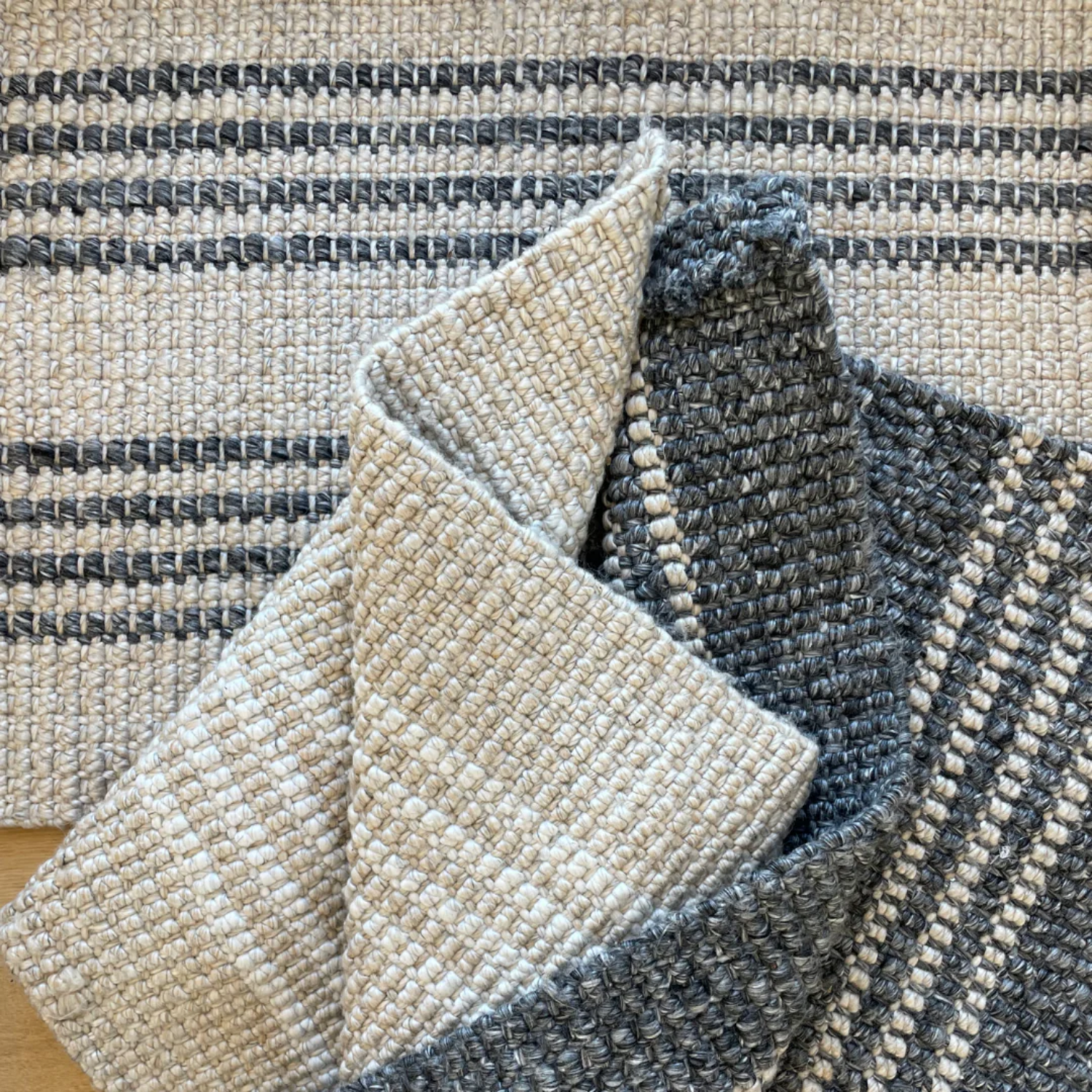 Close-up of textured mats in beige, gray, and black.