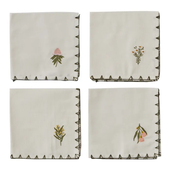 Four embroidered napkins with floral designs on a white background