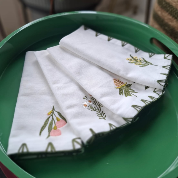White cotton napkin with floral embroidery on a green tray