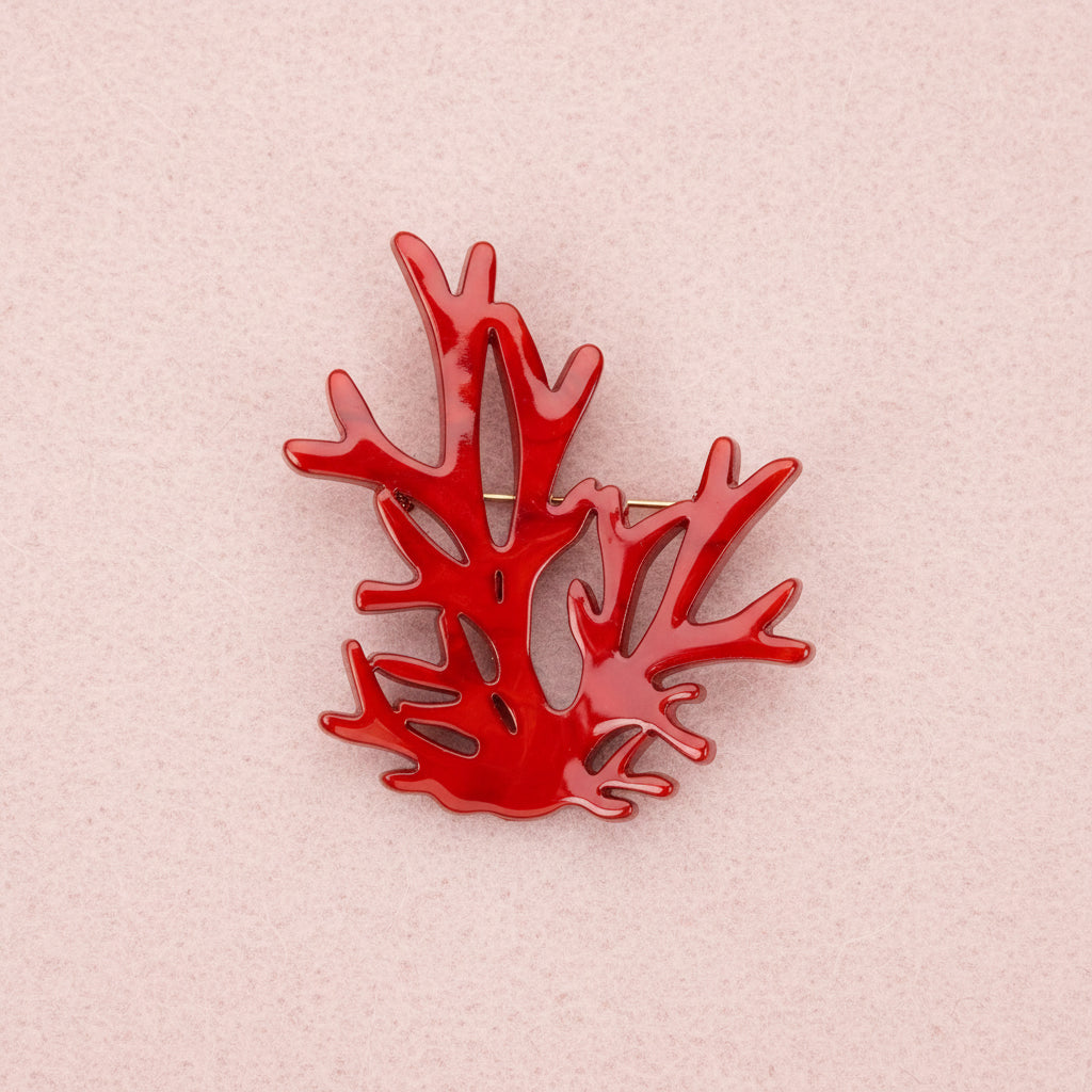 Red coral brooch on a pink background