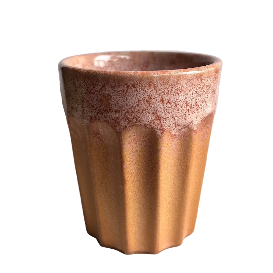 A handmade ceramic cup with a fluted, scalloped exterior and a speckled, glossy finish, shown on a neutral surface against a light gray background.