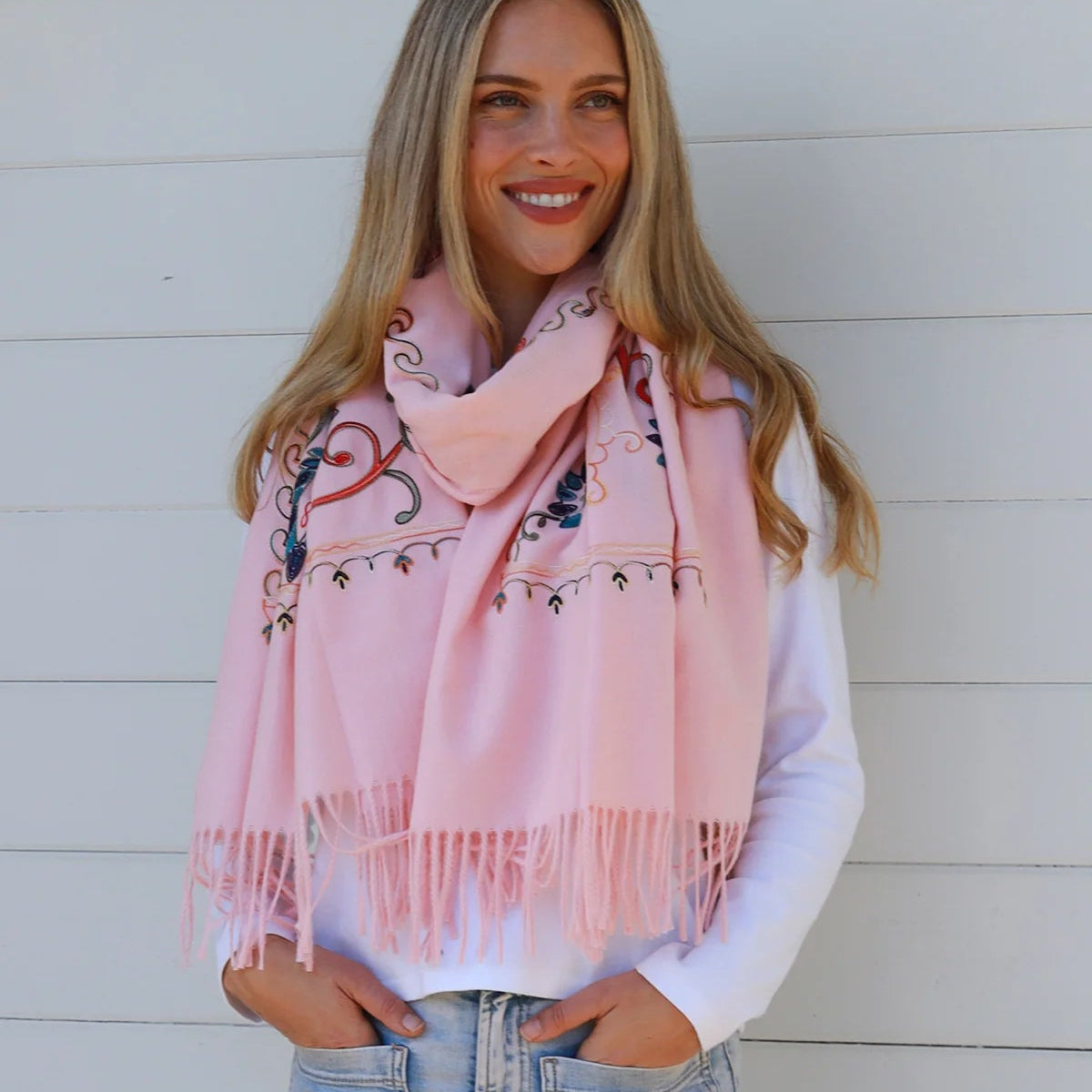 Woman wearing a pink scarf with floral patterns against a white background
