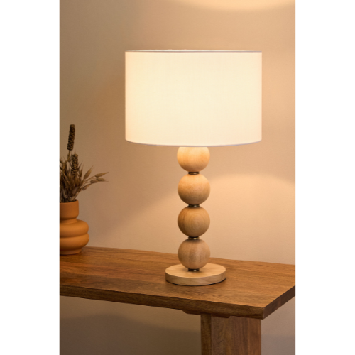 Table lamp with a wooden base and white shade on a wooden surface.