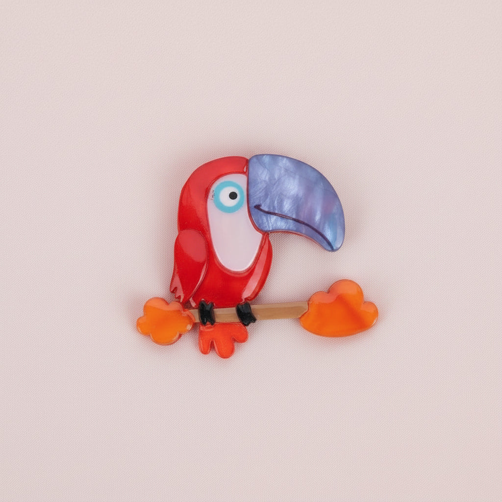 Toucan Brooch with red body and blue beak on a white background
