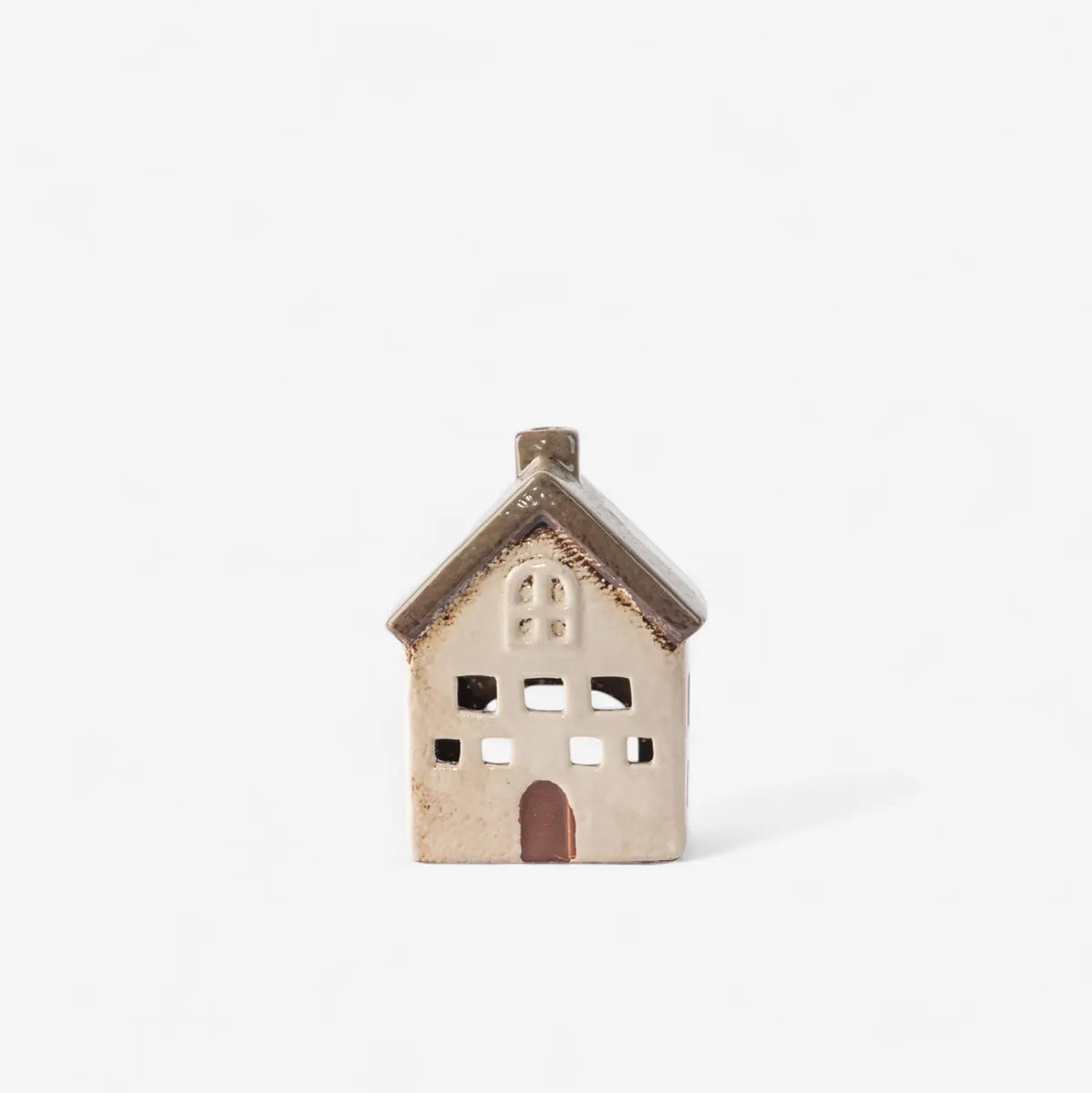 A small ceramic house-shaped candle holder with a textured beige and brown glaze, featuring cutout windows and a door, set against a plain white background.