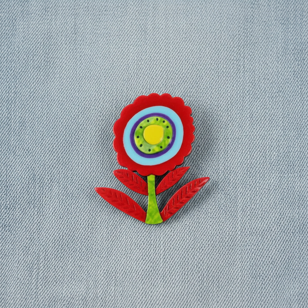 Colorful flower brooch with a red outline on a denim background