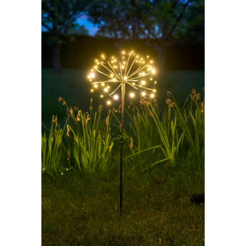 Decorative outdoor light fixture shaped like a flower in a garden at night.