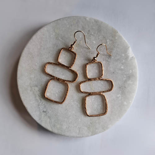 Pair of gold geo-shaped earrings on a marble surface