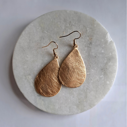 Gold teardrop earrings on a marble surface