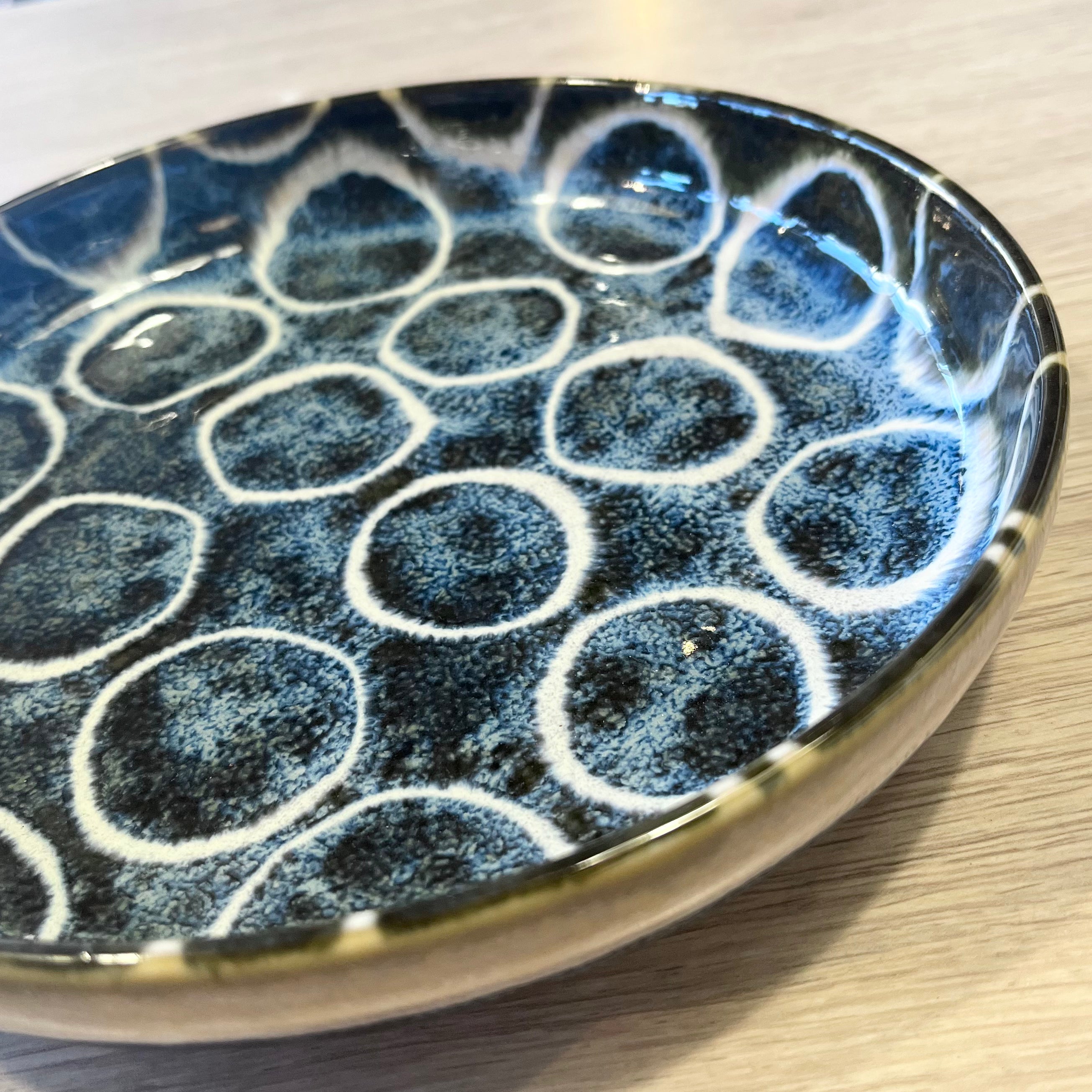 Ceramic plate with blue and white circular pattern on a wooden surface