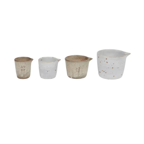 Set of four ceramic measuring cups with speckled design on a white background