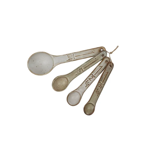 Set of four ceramic measuring spoons with measurements on them on a white background