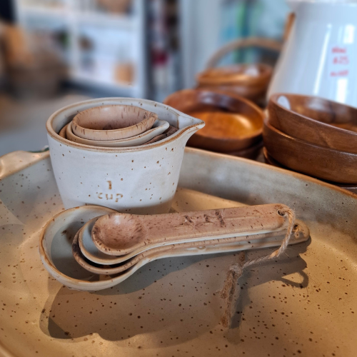 Set of ceramic measuring cups and spoons on a speckled surface with blurred background