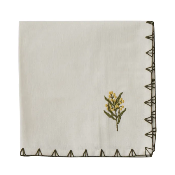Embroidered floral design on a folded white napkin with decorative border
