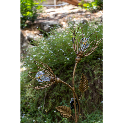 Decorative outdoor light fixture shaped like a flower with solar panel in a natural setting.