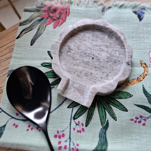 Decorative marble spoon rest and spoon on a floral placemat