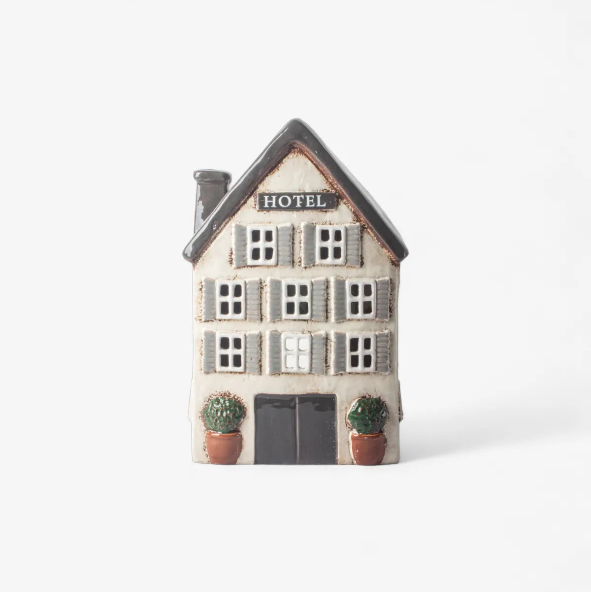 Decorative model of a hotel building with shutters and a sign on a white background