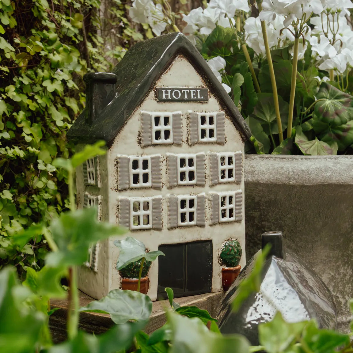 Tea light hotel surrounded by greenery and white flowers