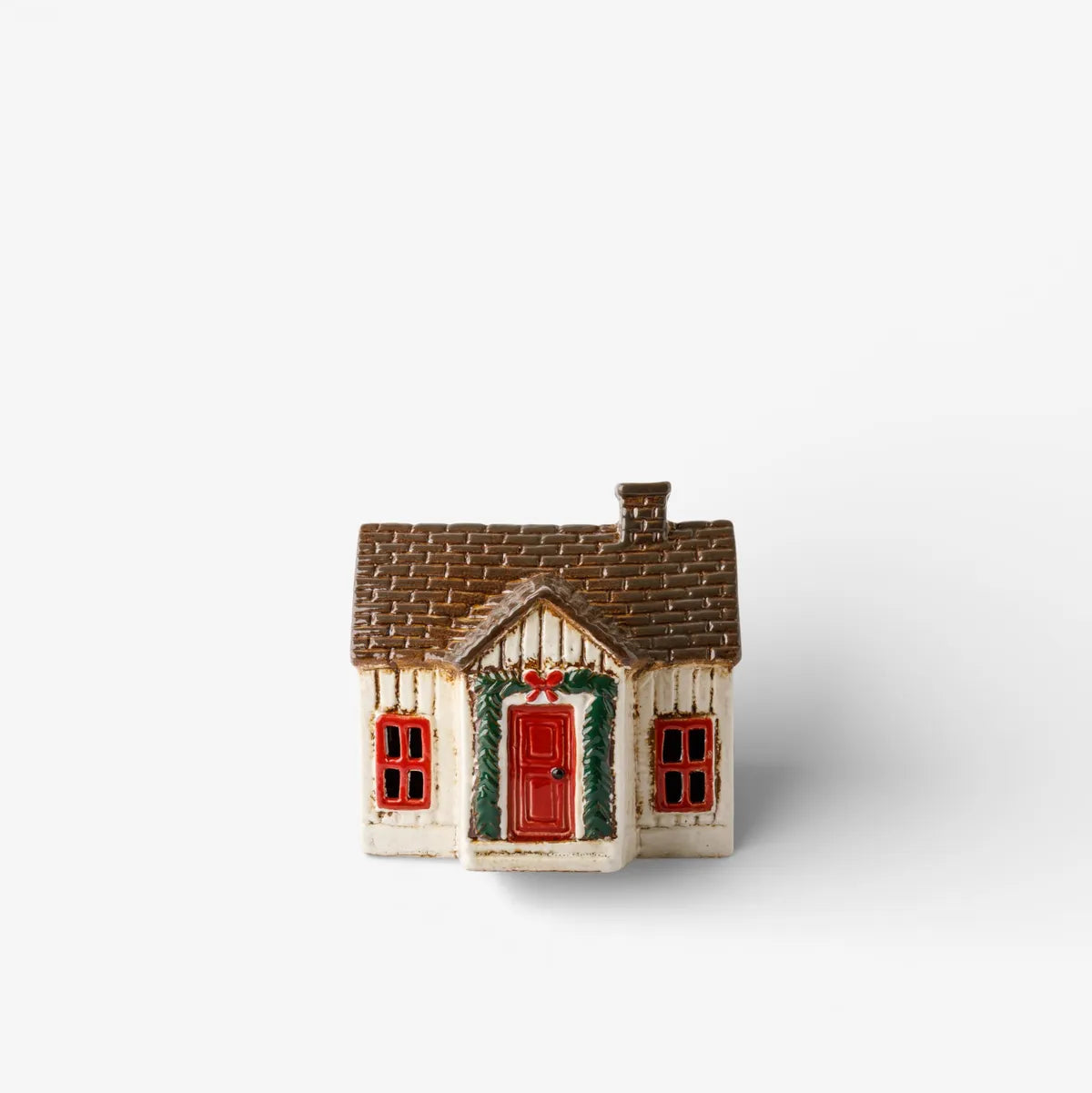 Small model of a house with a red door and greenery on a white background