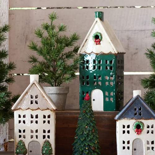 Decorative ceramic tealight houses with green and blue accents on a wooden surface.