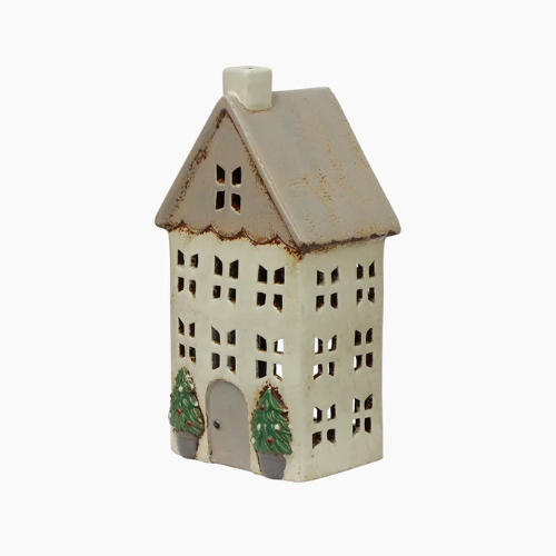 Ceramic house-shaped tealight holder with cut-out windows and green trees on a white background