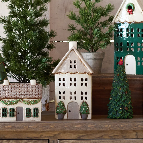 Decorative ceramic tealight houses with Christmas trees on a wooden surface