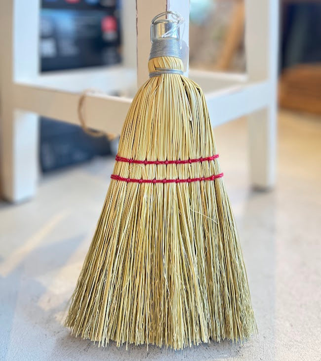 Broom with a red band on a light-colored floor