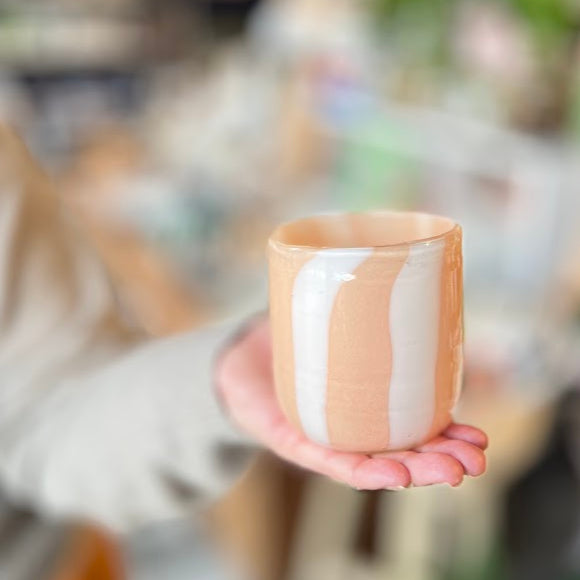 Person holding a glass candle with a blurred indoor background