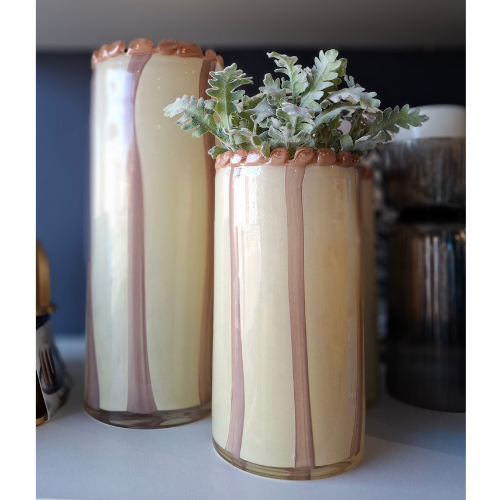 Pink and Nude Decorative vase with striped design and plant on a blurred background