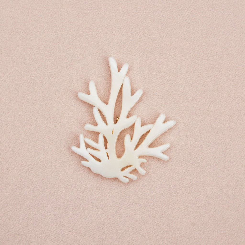 Decorative white coral brooch on a pink
background