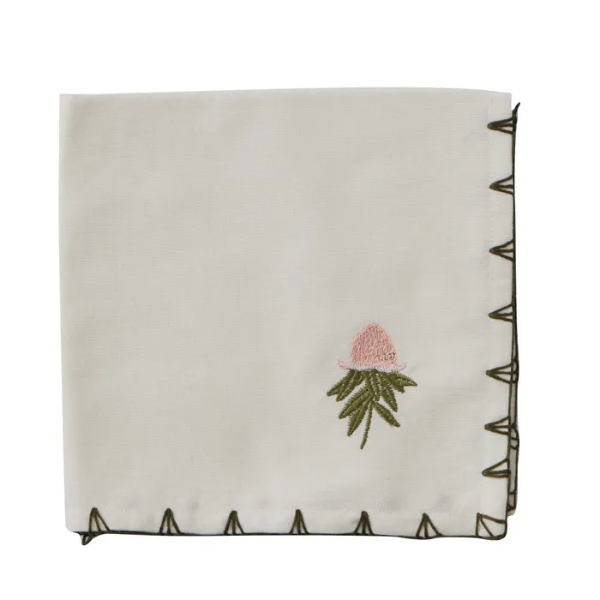 Embroidered floral design on a folded white napkin with decorative border