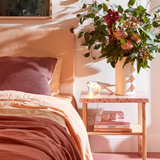 linen sheets in pinks, guava, terracotta, yellow, styled on a bed in sunshine